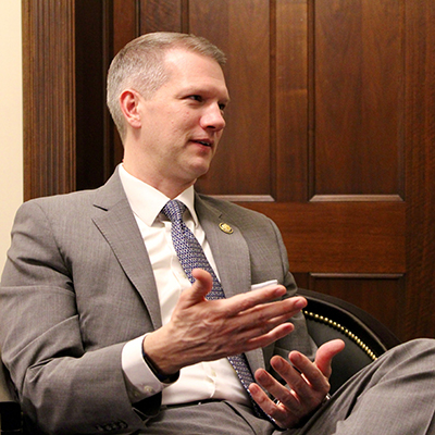 A man with short blond hair and wearing a gray suit looks to his left.